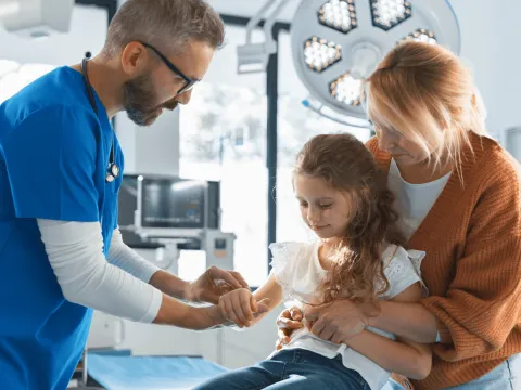 Doctor evaluating at a young girl's arm.