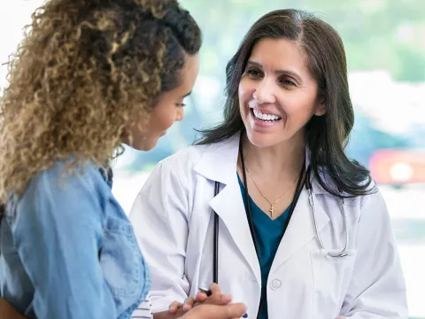 Doctor holding a clipboard and holding hands with a patient
