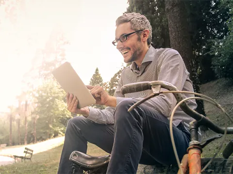 A man is sitting outside on the ground with a bicycle next to him.