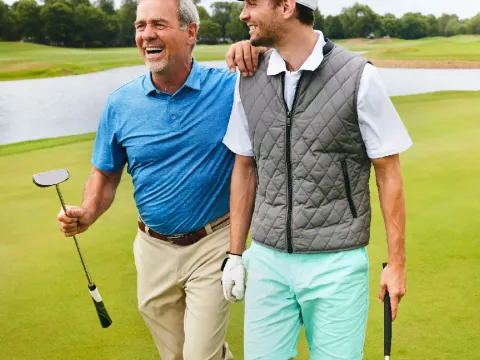 Two grown men walking away from a golf hole