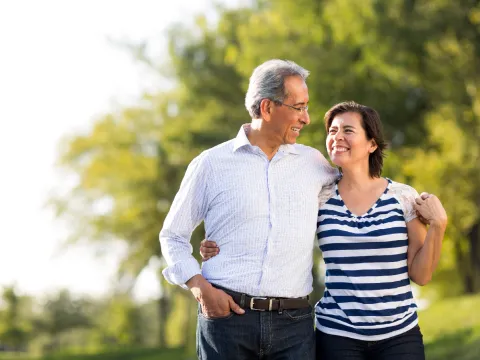 A mature couple walking while holding each other