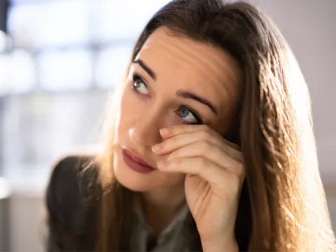 A woman rubs her eyes.