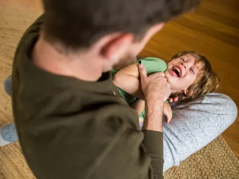 A dad is tickling his son.