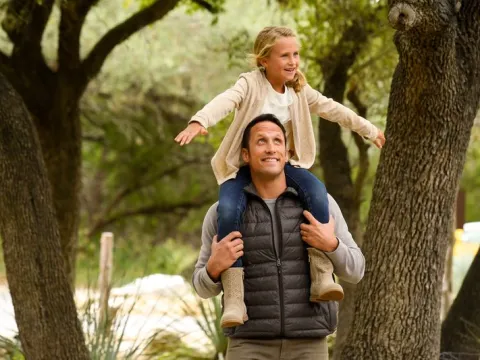 A girl sits on her dad's shoulders
