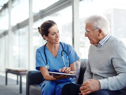 Nurse talking with older man at the hospital.