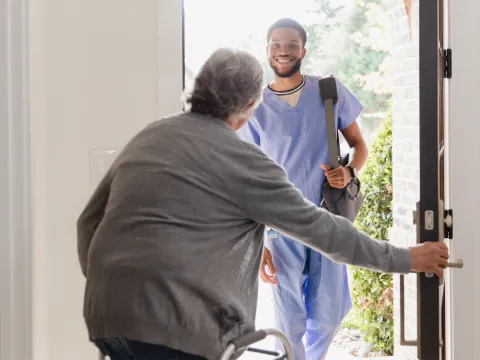 A Patient Opens Their Front Door to Allow a Therapist in Their Home