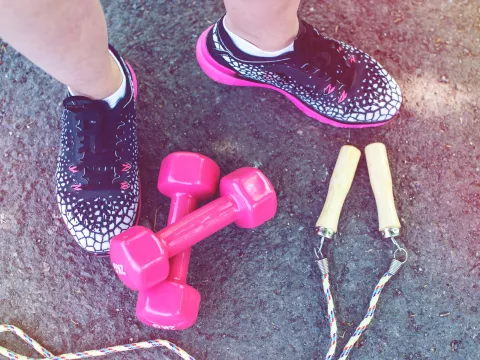 Close-up of workout shoes, weights, and a jump rope.