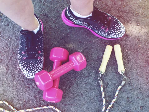 Close-up of workout shoes, weights, and a jump rope.