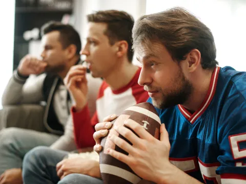 A group of men watch a football game excitedly.