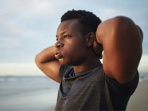 A teenage boy with a frustrated expression looks out over the ocean.
