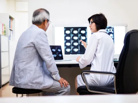 A doctor reviews brain scans with the older male patient