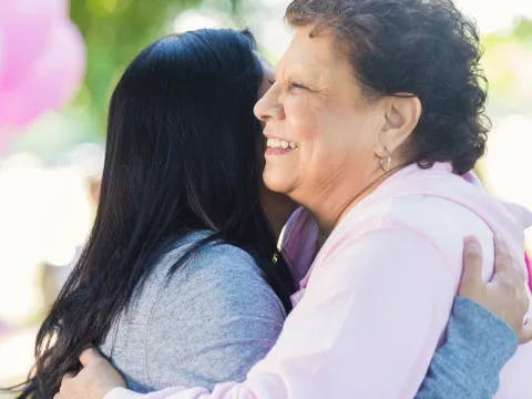 Two women hug at a breast cancer walk.