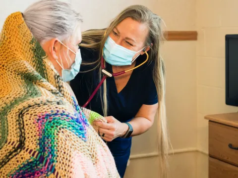 A caregiver comforts a patient as she uses her stethoscope