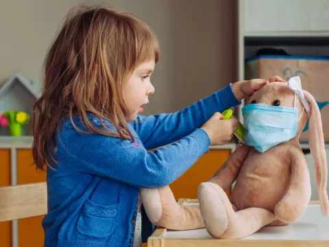 A child playing doctor with a stuffed animal.