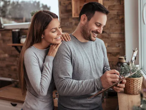 A couple making a list together in the kitchen.