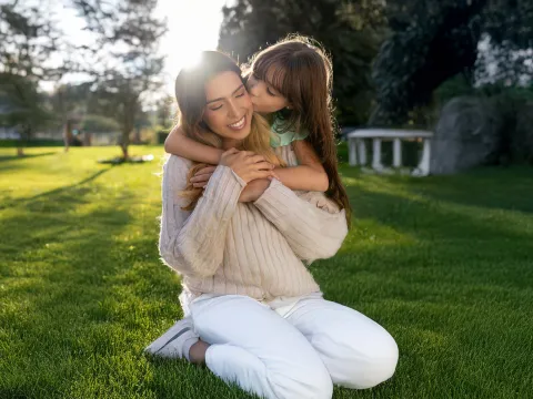 Mother and daughter embracing in yard