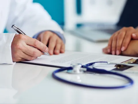 A doctor takes notes during a patient appointment.
