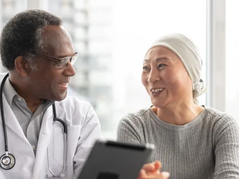 A doctor speaks with a patient undergoing cancer treatment.