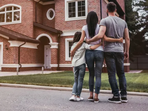 A family looks at their home from the curb.