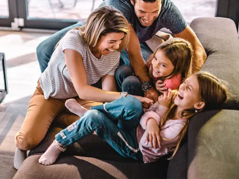 Happy family playing together on the couch.