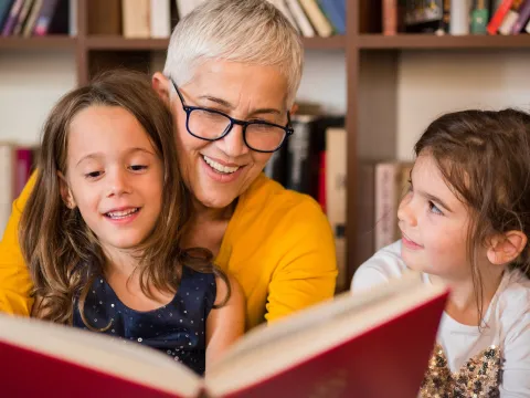 A grandmother reading to her granddaughters.