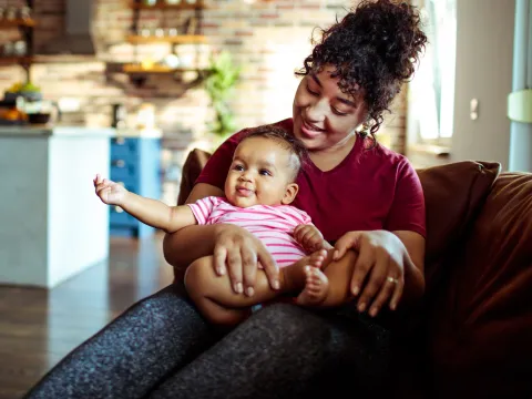 A mother and her infant sitting on the couch at home.