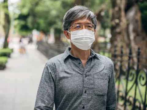 A man walking outdoors wearing a face mask.