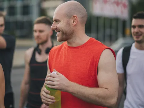 A man laughs with a group of friends after a workout.