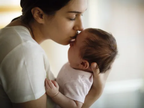 A mom kissing her infant.