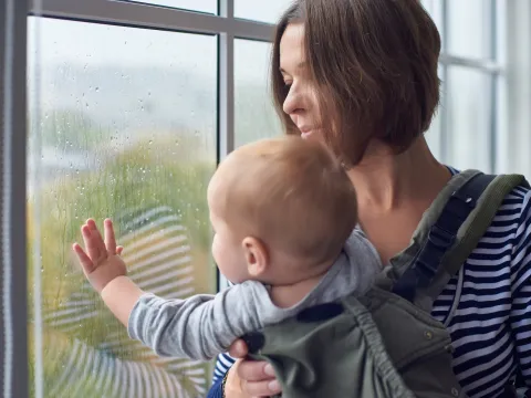 A mom keeps her baby safe indoors during a rain storm.