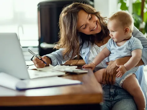 A mother and infant son at home in front of the computer.