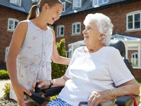 A grandmother plays with her grandchild in her power scooter.