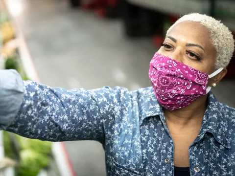 A woman wearing a cloth face mask at the grocery store.