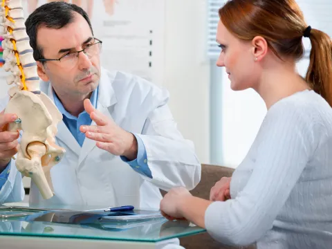 A woman discusses treatment options with her spine doctor.