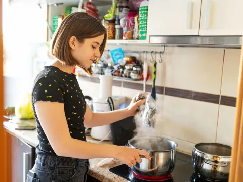 A young lady using her stove in the kitchen