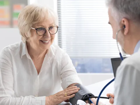 An older woman having her blood pressure checked by a doctor.