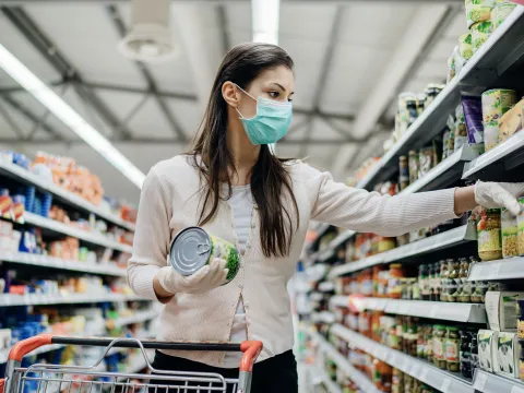A woman shopping at the grocery store wearing a mask.