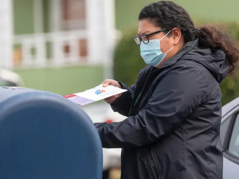 A woman dropping in her 2020 mail-in ballot