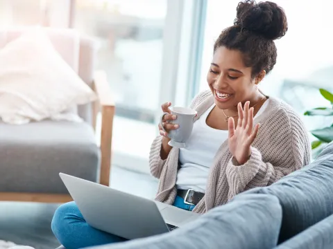A woman waving to a friend on a video call.