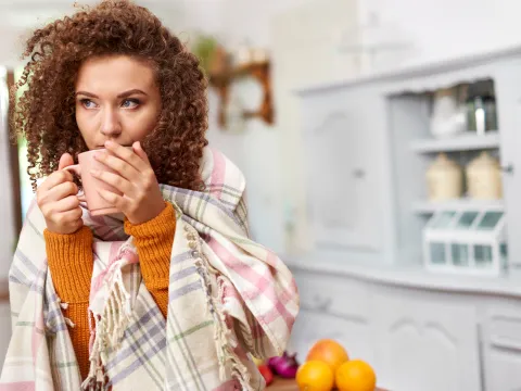 A woman sipping on her cup of coffee in her kitchen