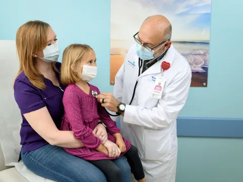 Doctor checking girl's heart beat