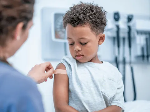 A young boy getting a band-aid after a flu shot.