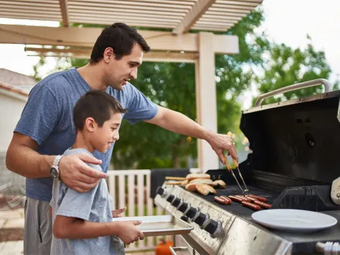 A father and son grilling on the porch.