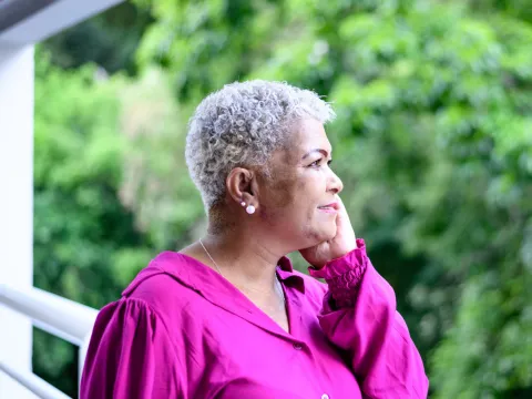 An older woman talking on the phone outdoors.