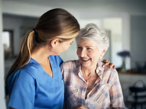 Nurse embracing senior woman at home