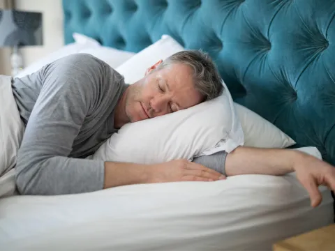 Man sleeping on his side in a bed.