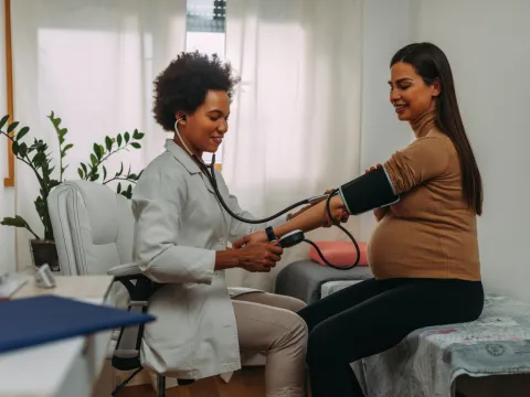 Pregnant woman getting her blood pressure checked by a physician.