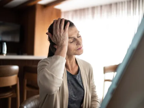 An older woman holding her hand to her head.