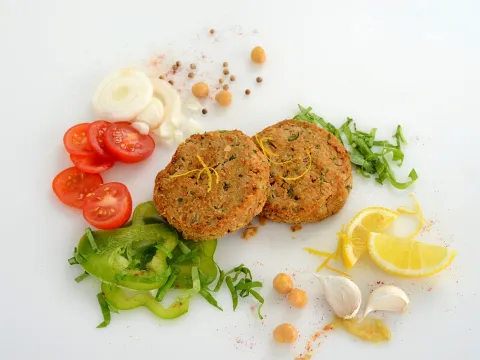 two falafel patties in the center of veggies and seasonings