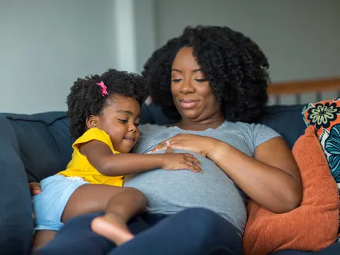 A mother having her daughter touch and feel her baby belly